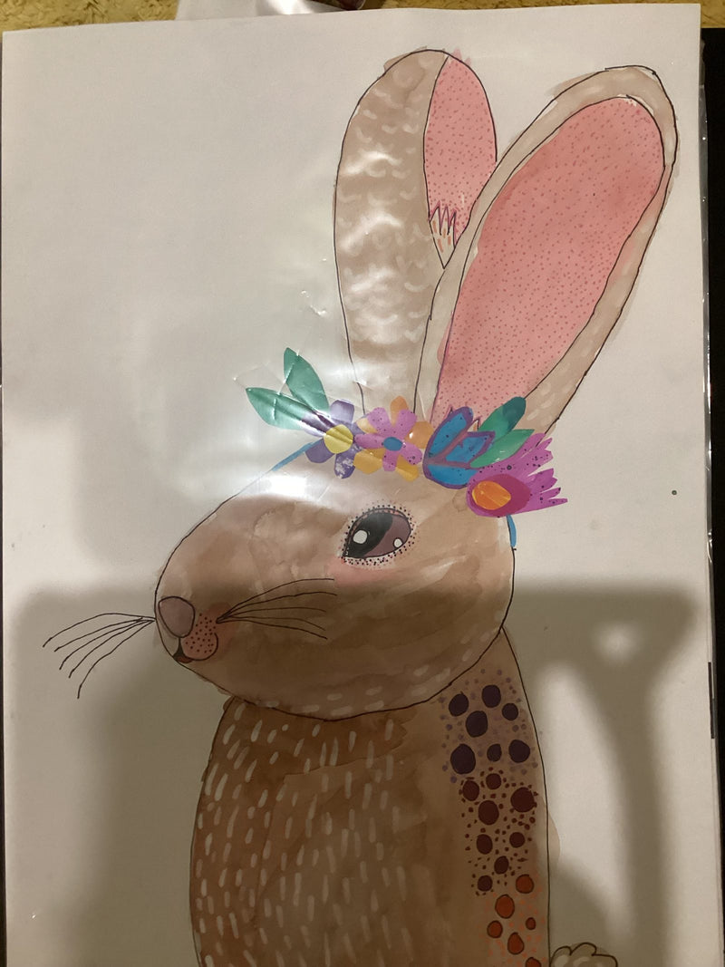 A detailed hand-drawn and painted illustration of a brown rabbit in profile, wearing a colourful flower crown with purple, pink, orange, teal, and blue flowers. The rabbit has pink inner ears, delicate whiskers, and decorative circular dot patterns on its body.
