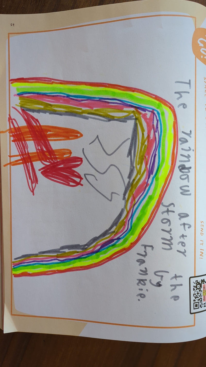 A colourful crayon and marker drawing of a large rainbow arc made up of many bright stripes including red, orange, yellow, green, blue, and purple. The rainbow curves across the page with some grey storm cloud shapes sketched in the middle.