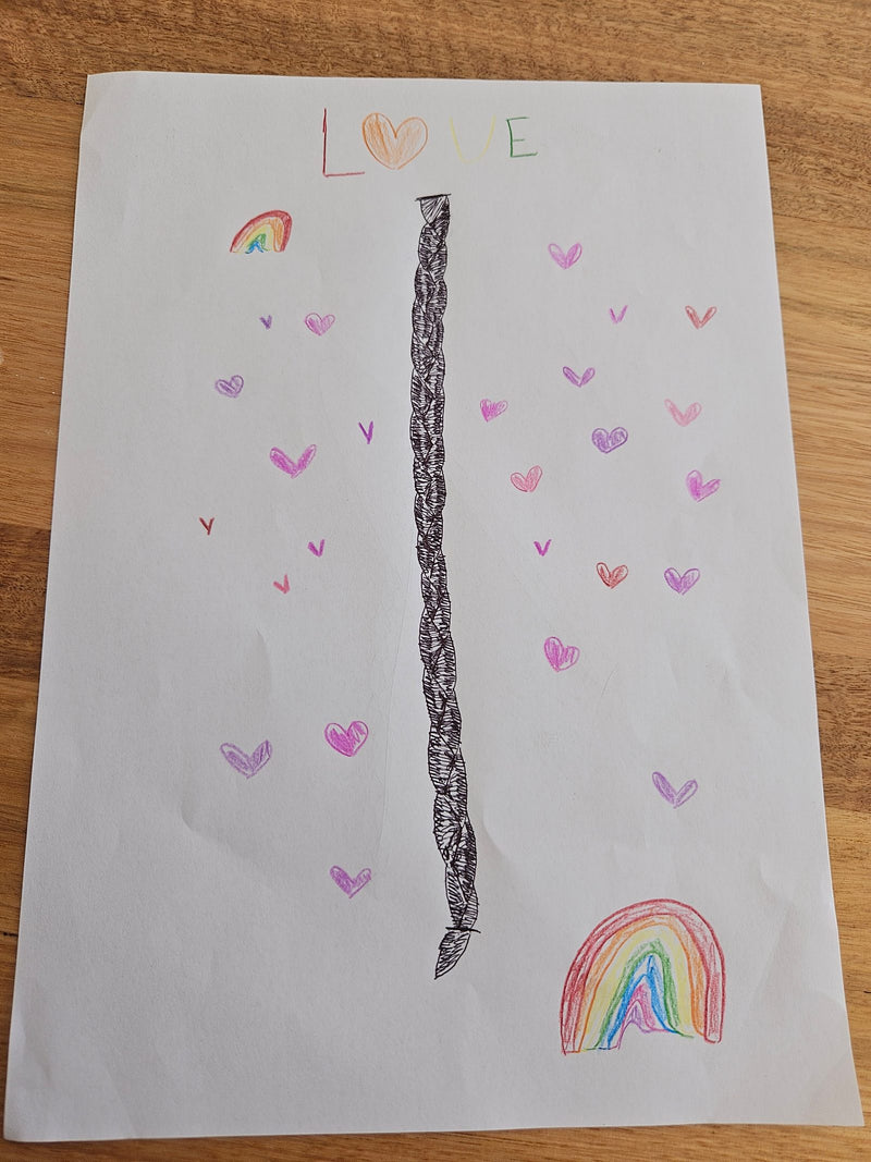 A hand-drawn artwork on white paper featuring the word 'LOVE' at the top in colourful letters, with a detailed braided pattern running vertically down the centre of the page. The drawing is decorated with numerous pink, purple, and red hearts of various sizes, and two small rainbow illustrations in the upper left and lower right corners.