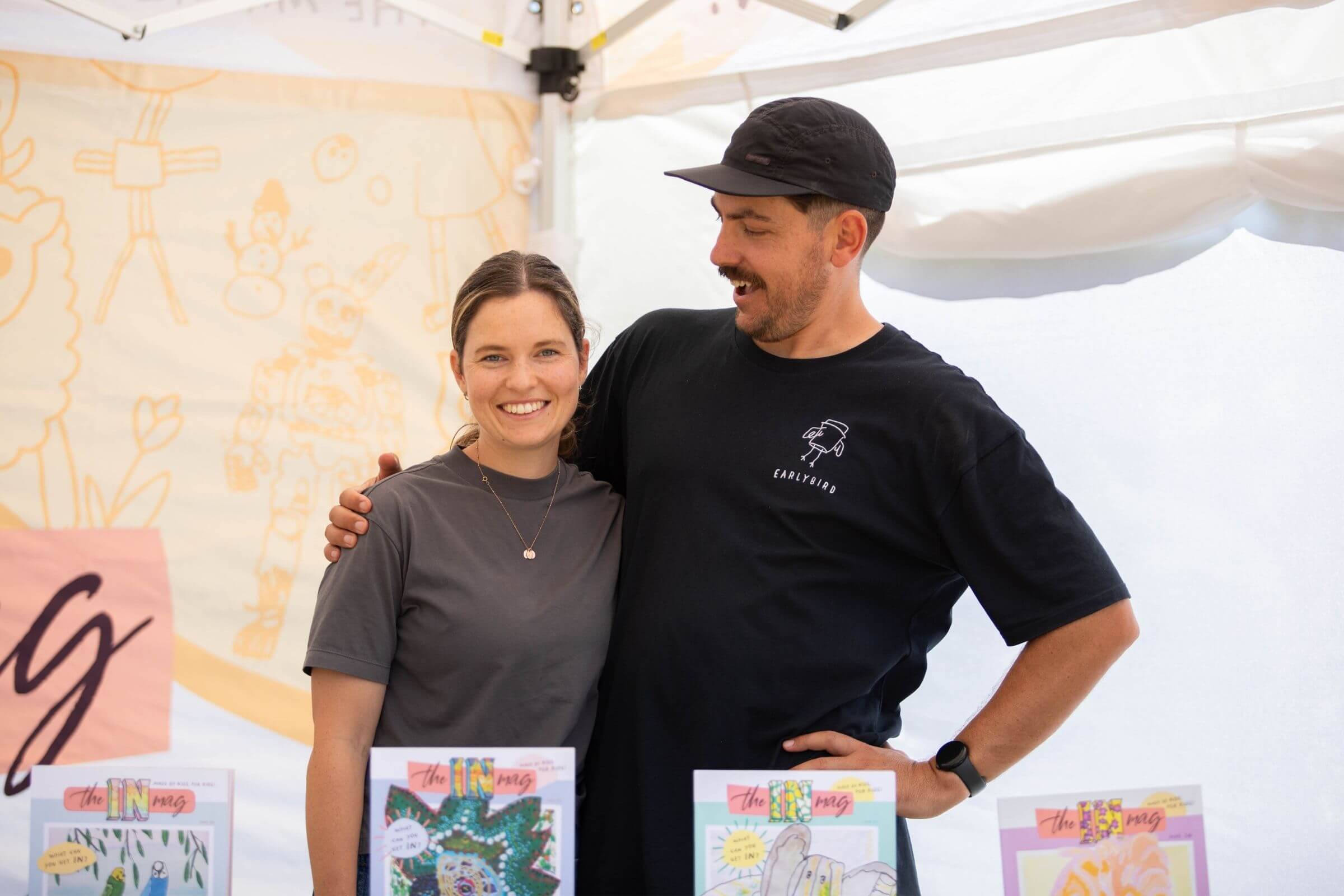 theINmag founders Ryan and Tam at a market with their copy of the magazine.