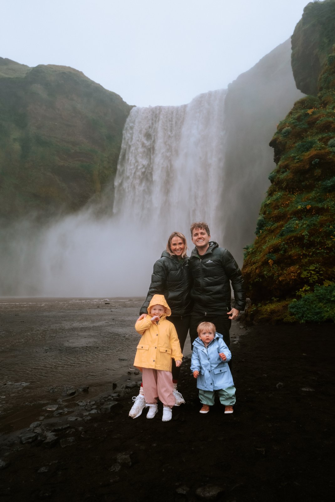 The family in raincoats in front of a huge waterfall in Iceland.