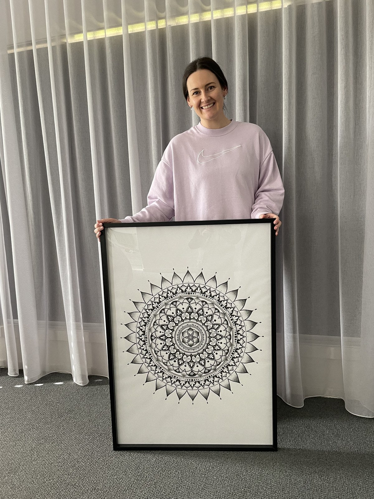 Leah holding a detailed hand-drawn mandala artwork.
